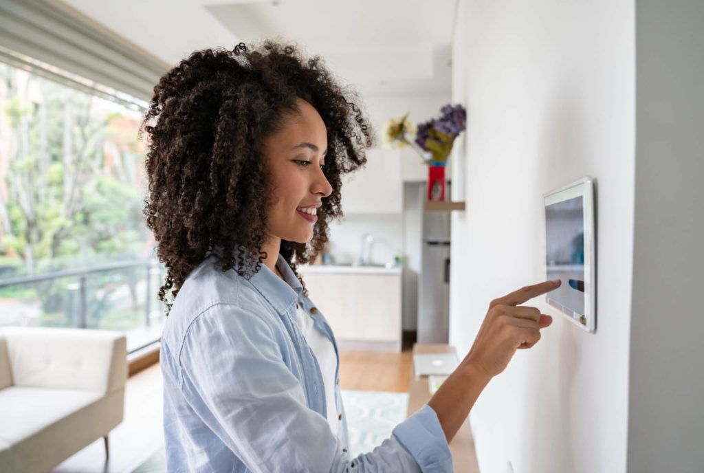 Woman adjusts smart home settings on a wall panel