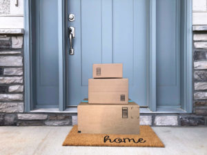 Brown cardboard packages piled on a porch in front of a blue front door