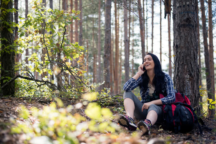 female hiker chatting on the phone in the woods