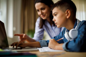 A mom helps her teenage son with homework on the computer