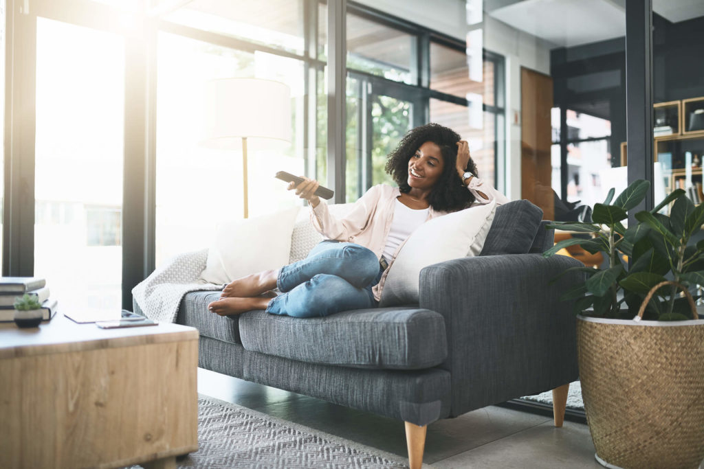 Young woman relaxing at home watching TV on her 4K TV