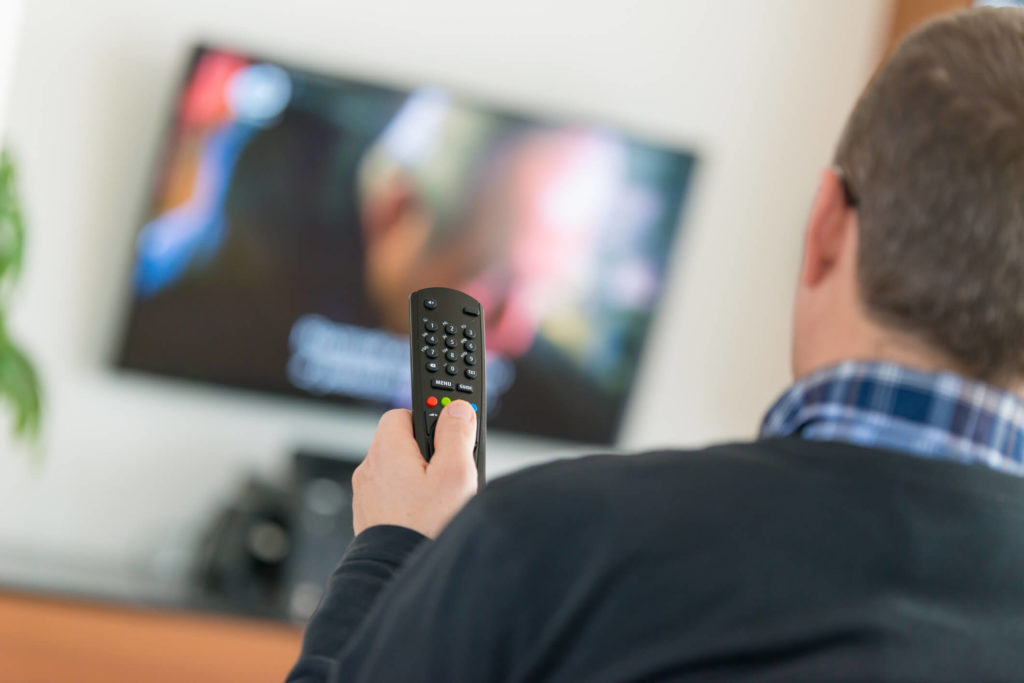 Man controlling TV with remote