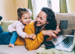 Mom and daughter laying on couch in front of laptop