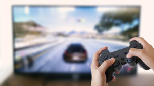 Boy holding game console with car racing game on 4K TV in background