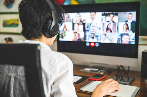 An Asian man joins a video call on his desktop computer