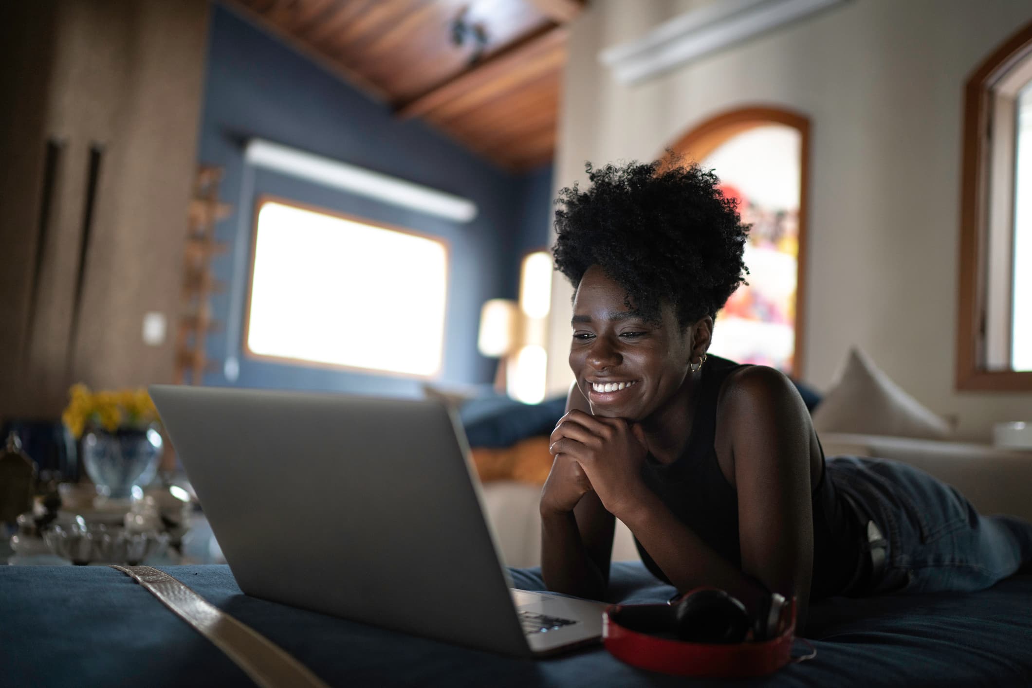 Woman streaming on laptop while laying on stomach on living room couch