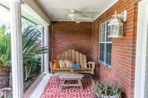 View of leisurely front porch with wooden bench, rug, and coffee tables