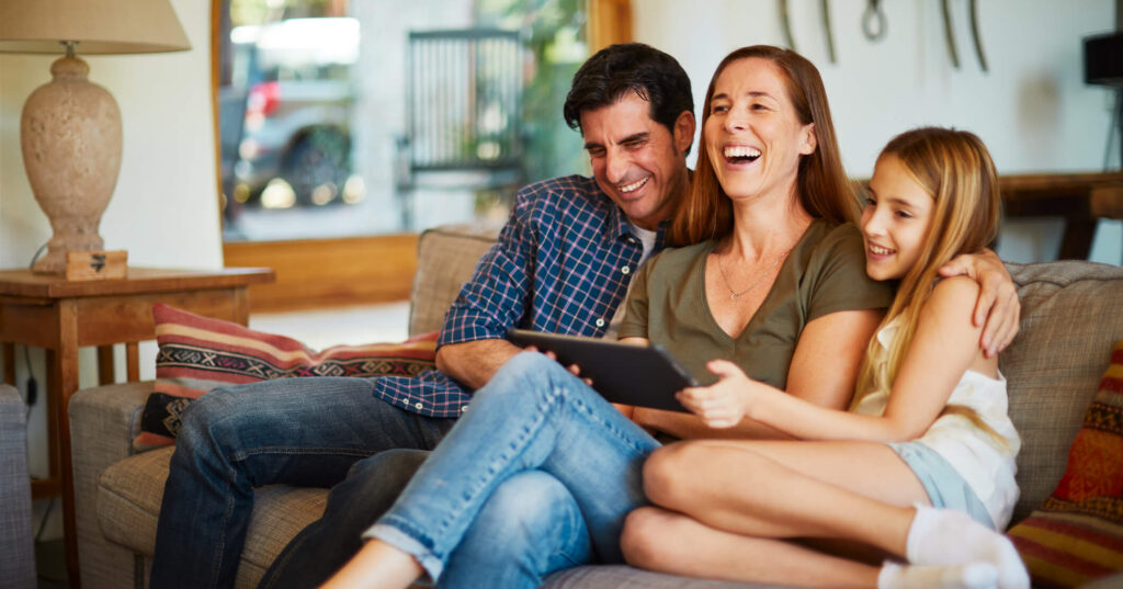 Man, woman, and young girl watch videos on a tablet