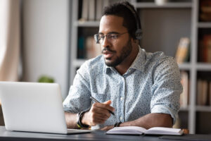 Man works at computer with a pen and journal