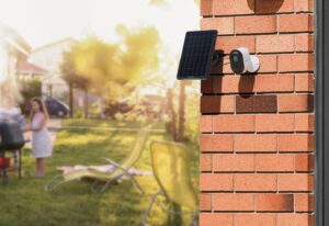 Reolink Argus 3 and solar panel mounted on a brick wall near a yard