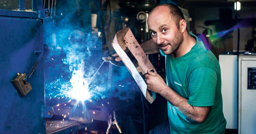 Photograph of a bald man welding