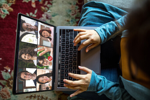 A downward view of a woman chatting in a video call on her laptop.