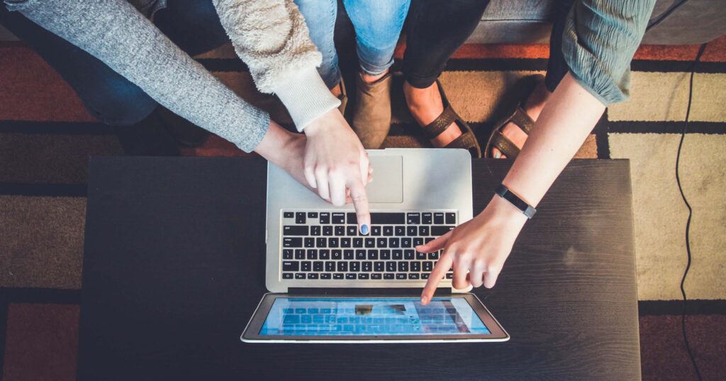 a top-down shot of three friends on a laptop choosing an internet plan