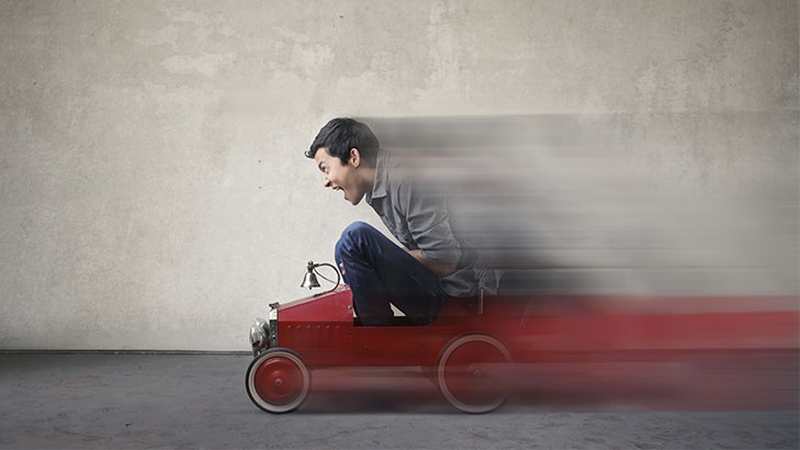 man travelling fast in small red car