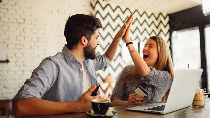 Couple high fiving over a laptop