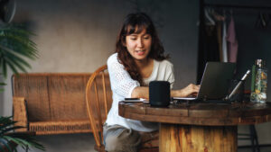 Woman talks to Alexa device while working on a laptop