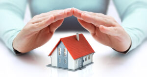 hands covering house - insurance concept - real estate