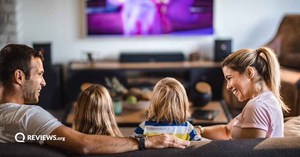 Mom, dad, daughter, and son sitting on living room couch watching TV