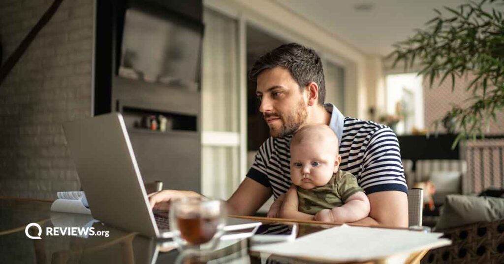 man using laptop while holding baby