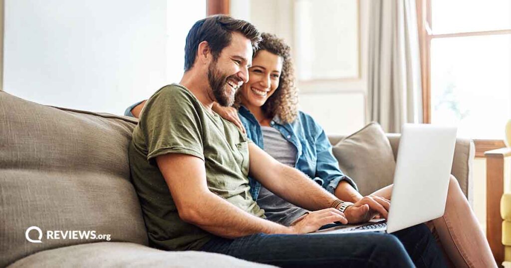 happy couple sitting on the couch using a laptop together