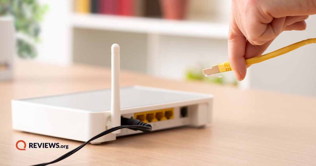 person plugging in router on a wood desk