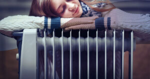 young girl lazing on an oil column heater